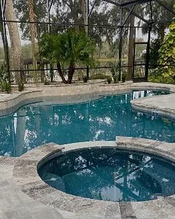 A screened lagoon shaped pool with a round spa, looking out over the lake behind the house.